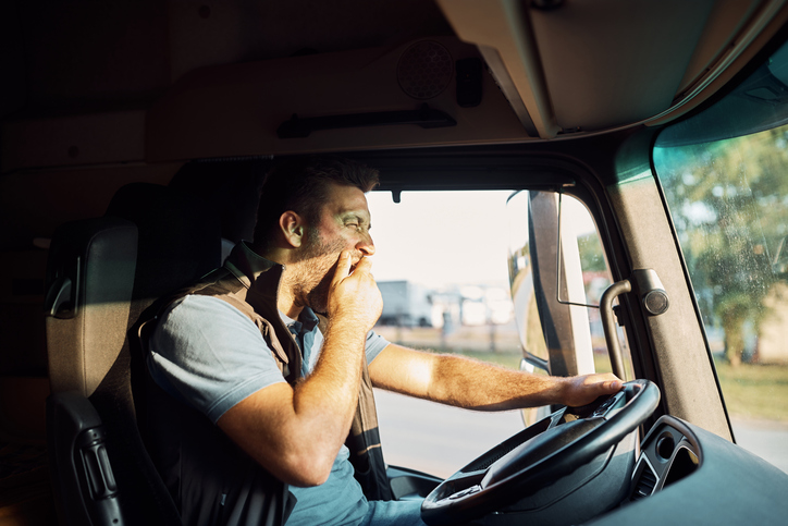 Exhausted driver yawning while driving a truck.